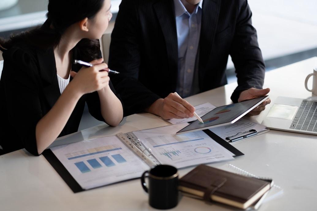 Two colleagues reviewing charts on paper and a tablet