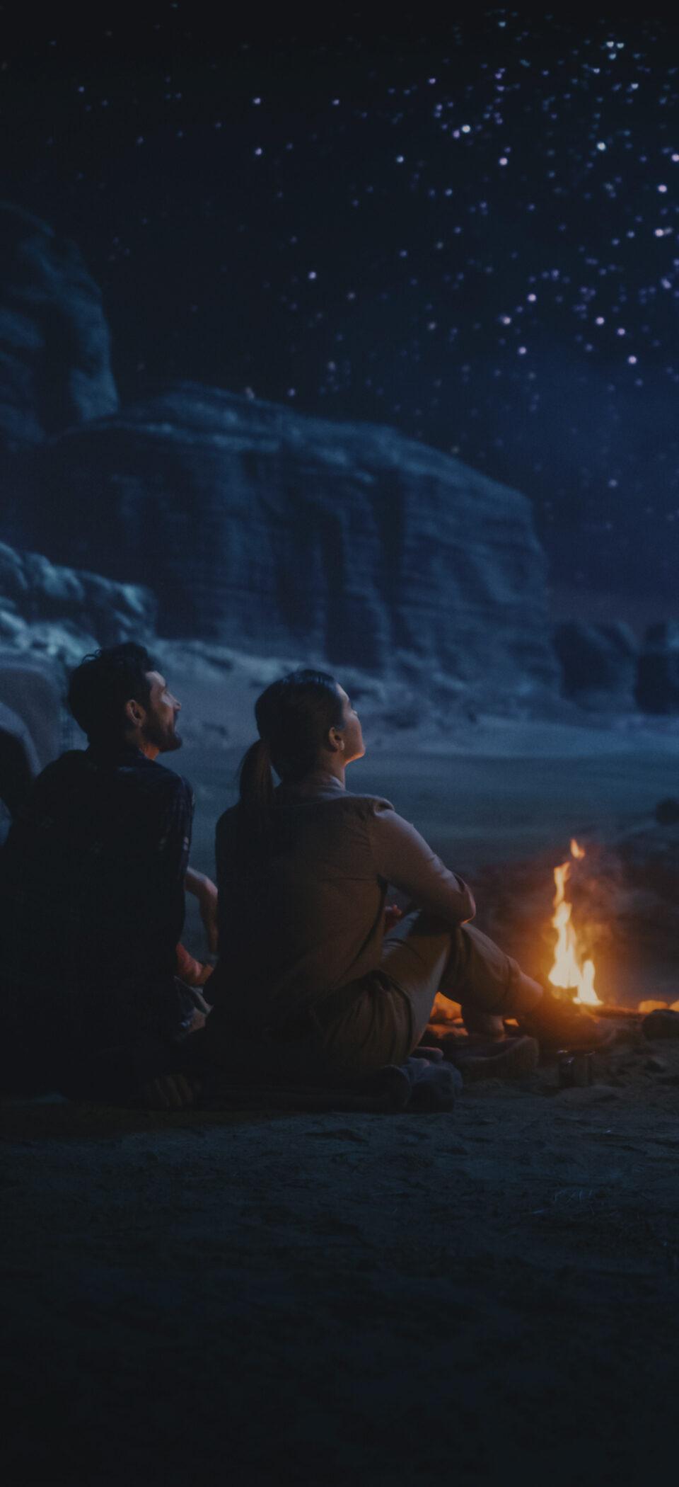 Campfire glowing beneath a starry night sky