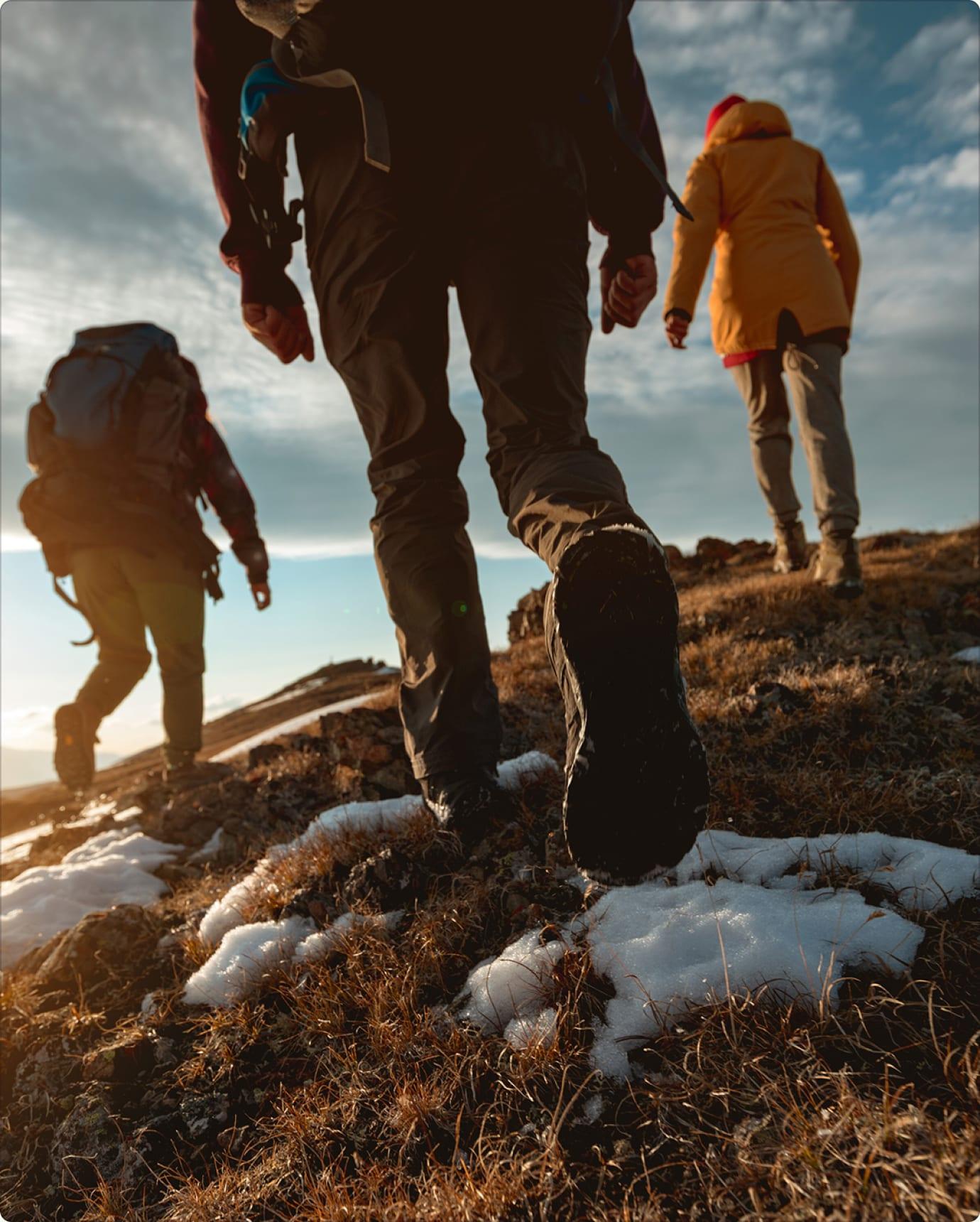 Hikers climbing a frosty hillside at sunrise