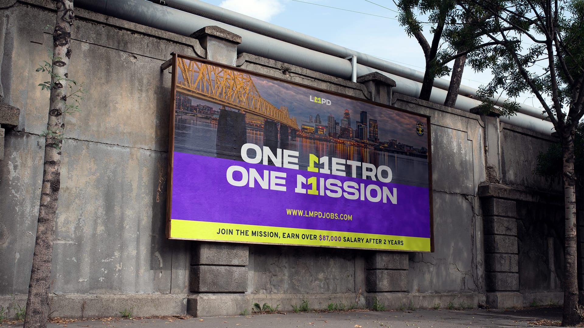 Large One Metro One Mission billboard on a concrete wall showing the Louisville skyline at sunset